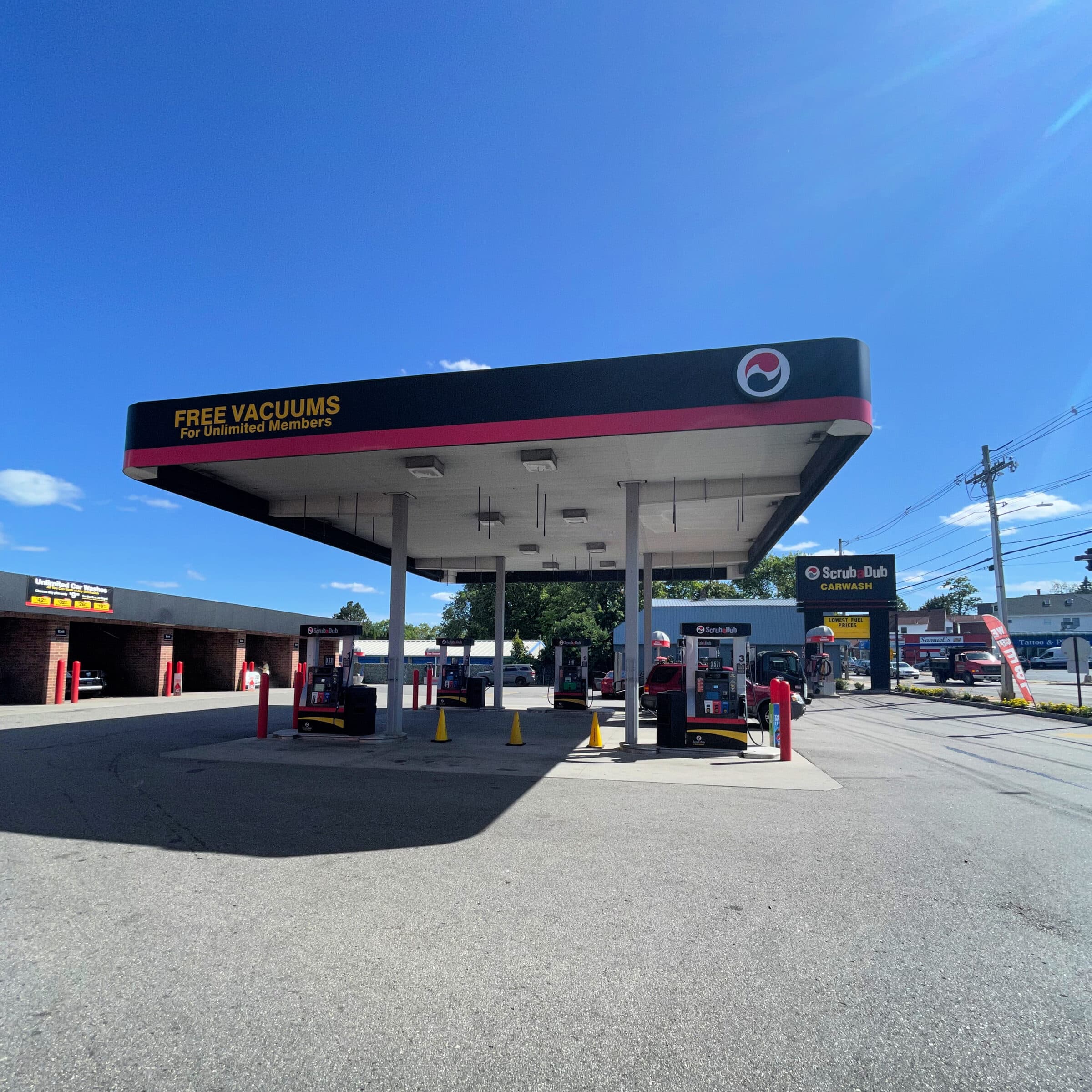 ScrubaDub gas station canopy reading "Free Vacuums for Unlimited Members" over ScrubaDub-branded pumps