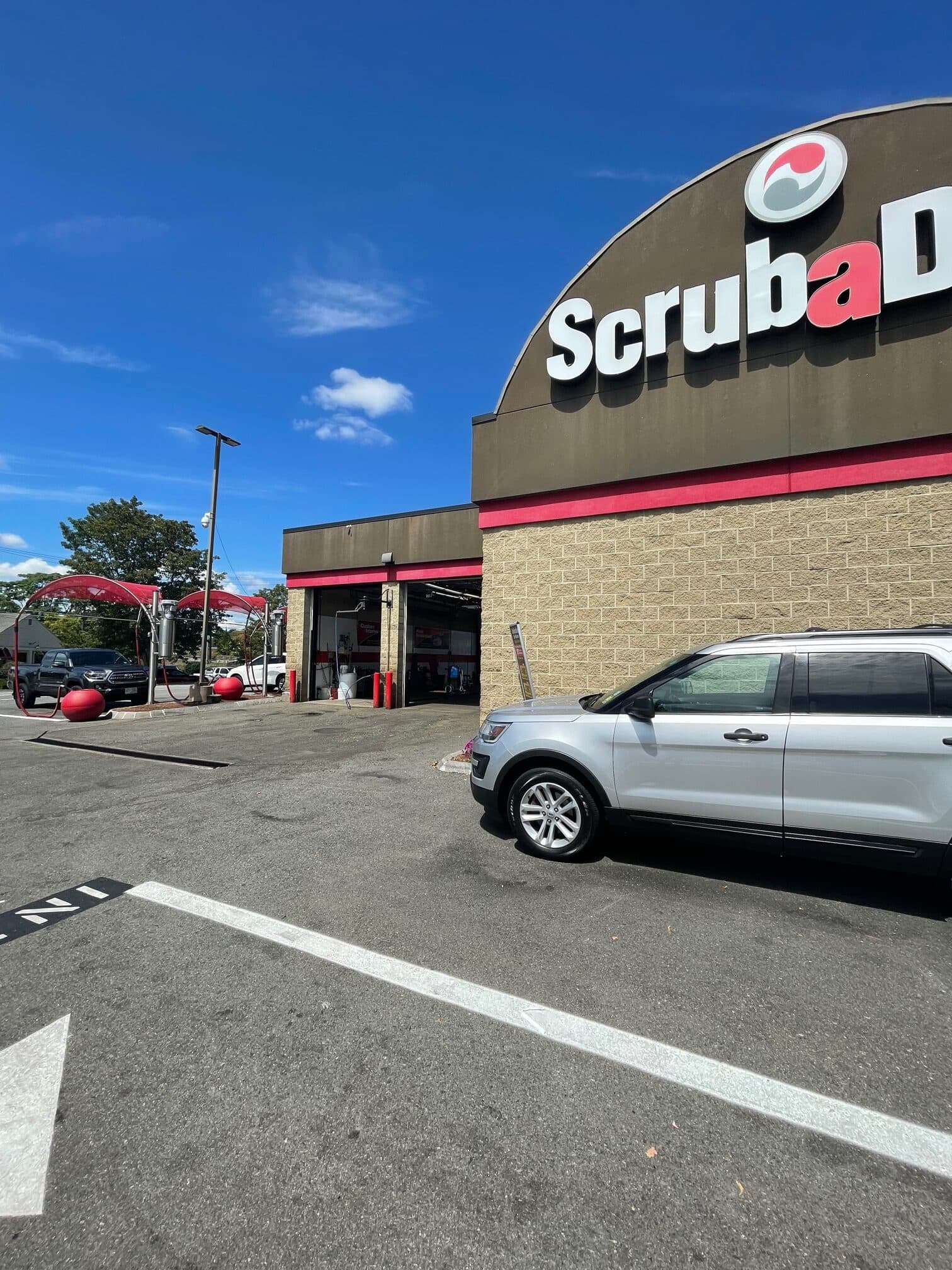 ScrubaDub Woburn building with a large arched ScrubaDub sign, service bays, and red vacuum canopies