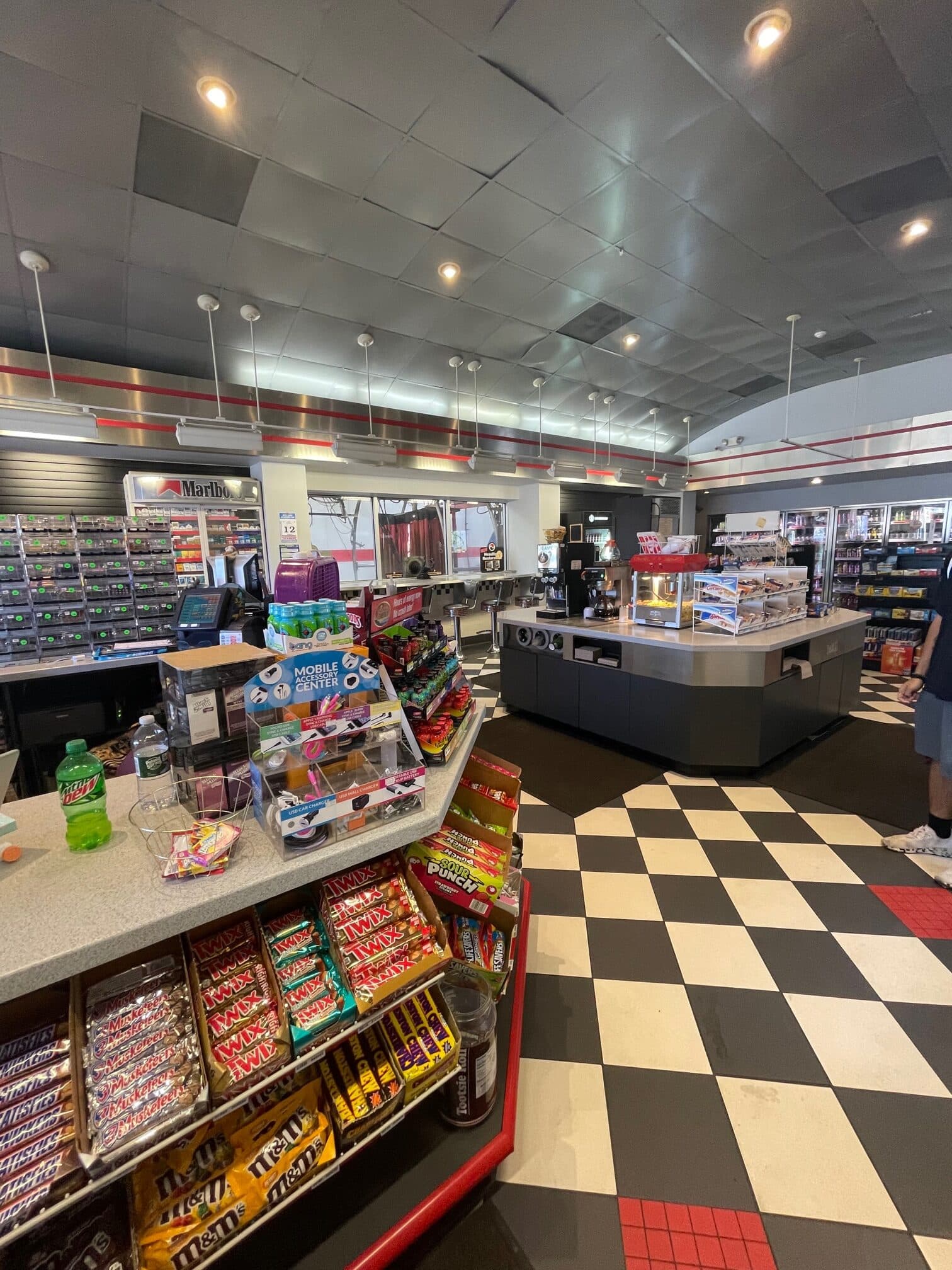 Convenience store with candy displays, a coffee and popcorn island, and a black-and-white checkered floor