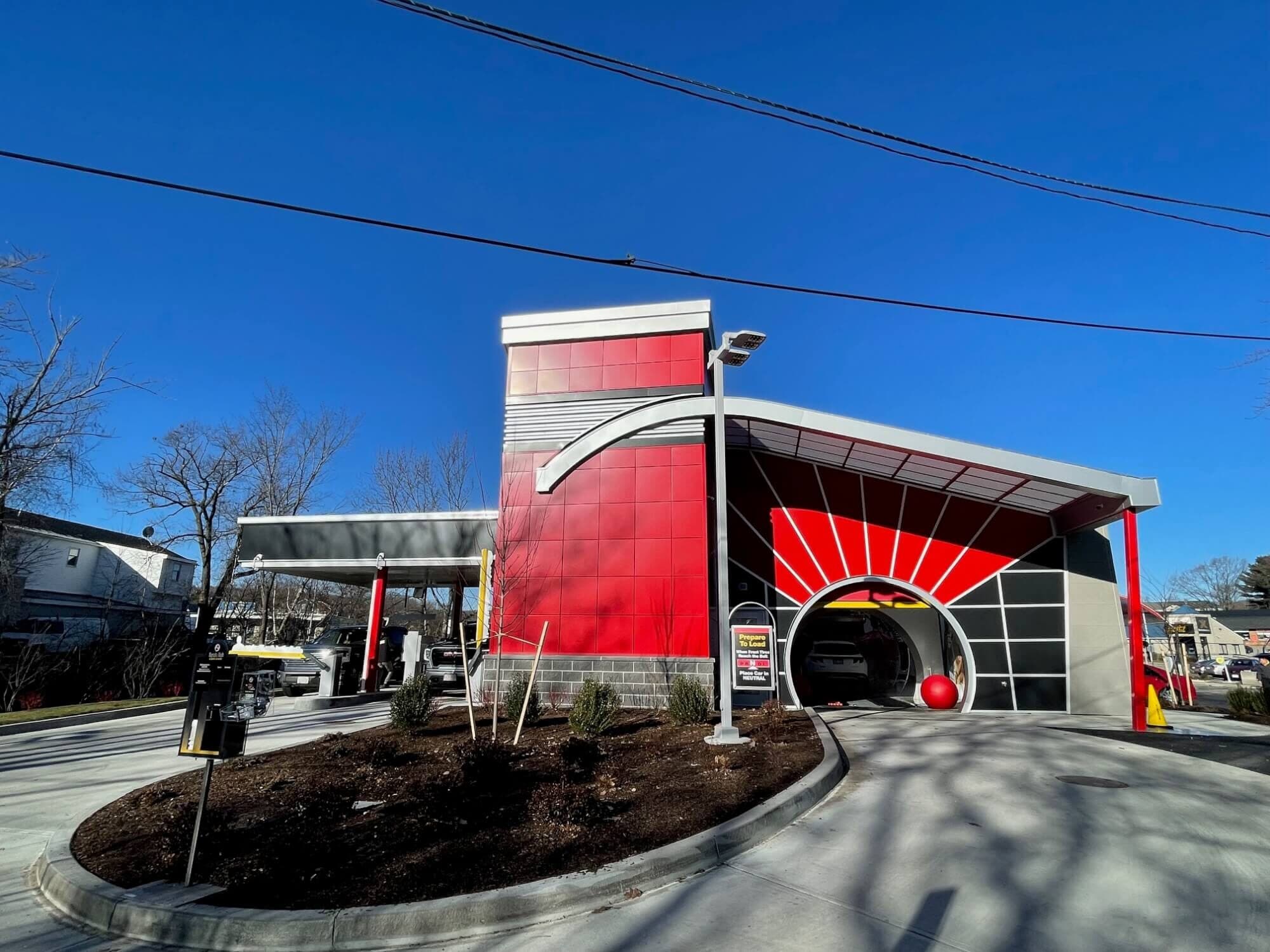 Side of the ScrubaDub Worcester Park Ave car wash with a red tower, sunburst tunnel entrance, and pay lanes