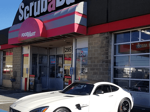 White Mercedes-AMG GT parked in front of the ScrubaDub Woburn FoodMart entrance