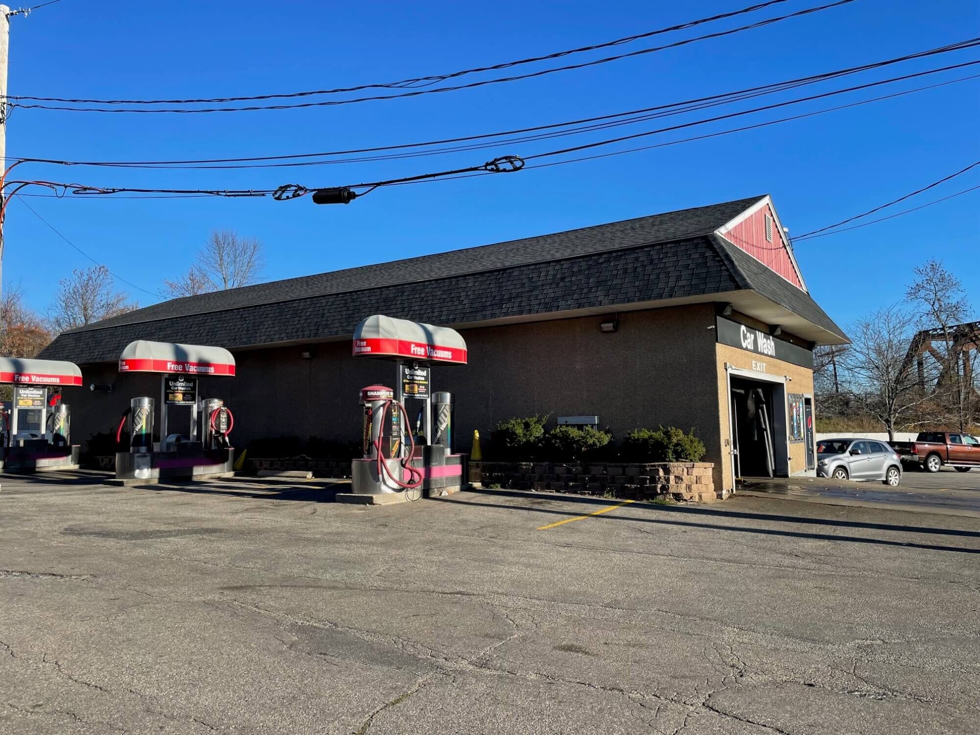 Row of ScrubaDub free vacuum stations with red-striped canopies beside a car wash building