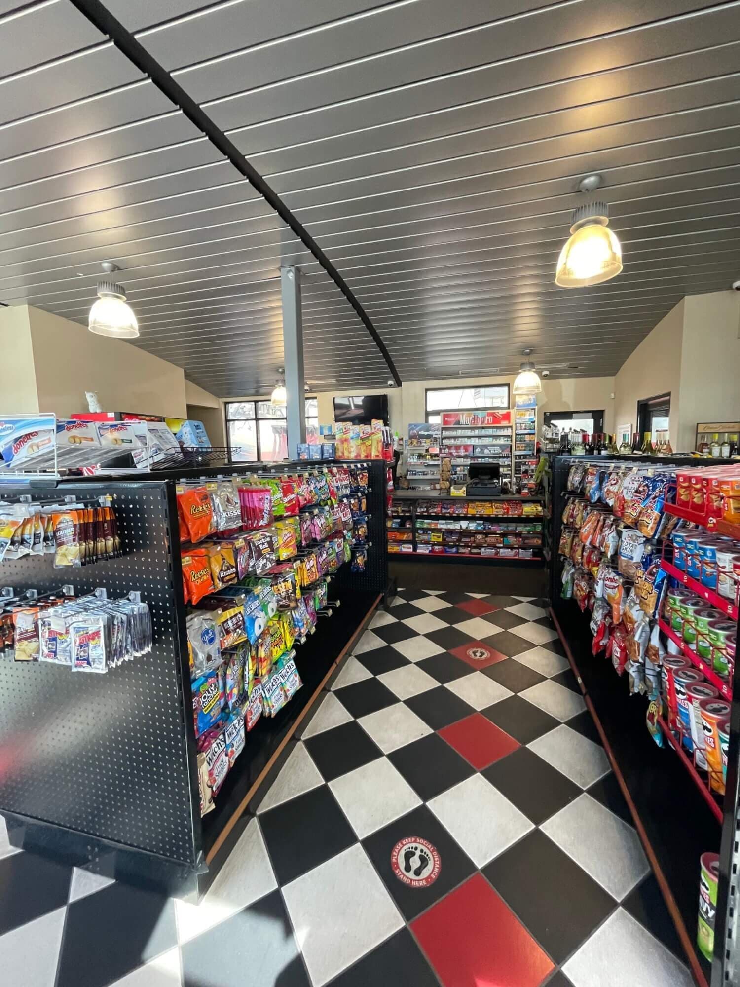 Convenience store aisles with snacks and candy on a black-and-white checkered floor