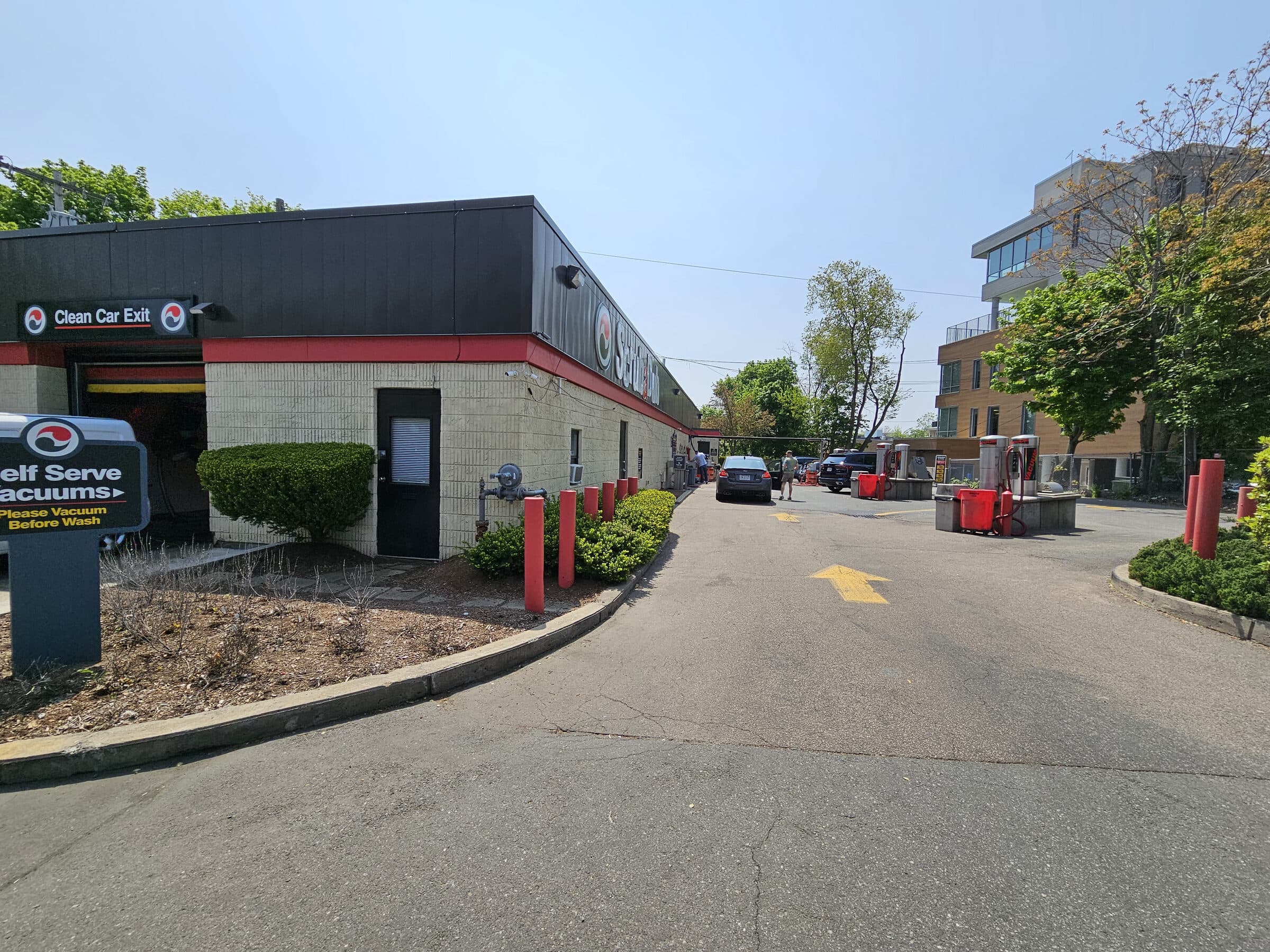 ScrubaDub Brookline building with a "Clean Car Exit" sign, a self-serve vacuum sign, and vacuum stations along the drive