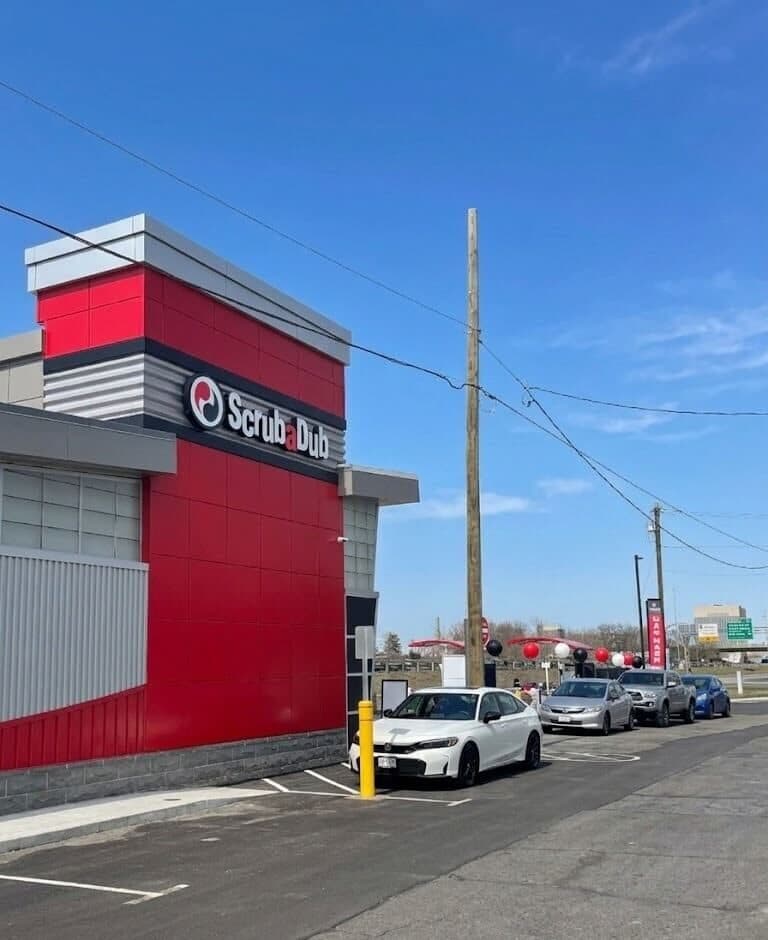 Cars lined up beside the red ScrubaDub tower at the new Medford car wash