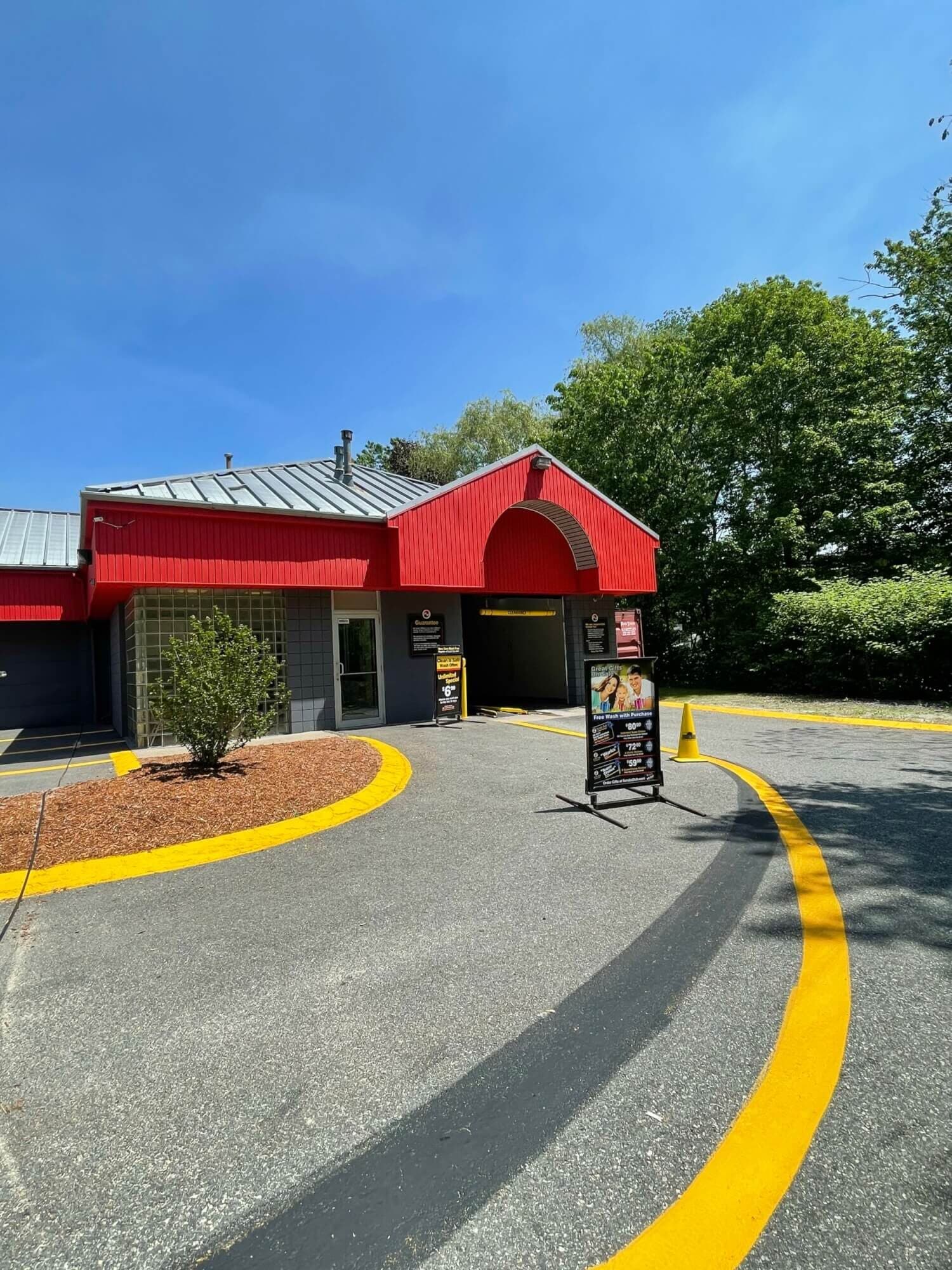 Red-gabled ScrubaDub Salem tunnel entrance with curving yellow lane lines and a gift card sign