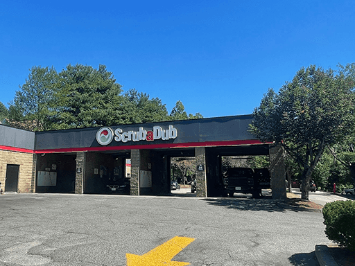 ScrubaDub Marlborough car wash with a black fascia over open wash bays among tall trees