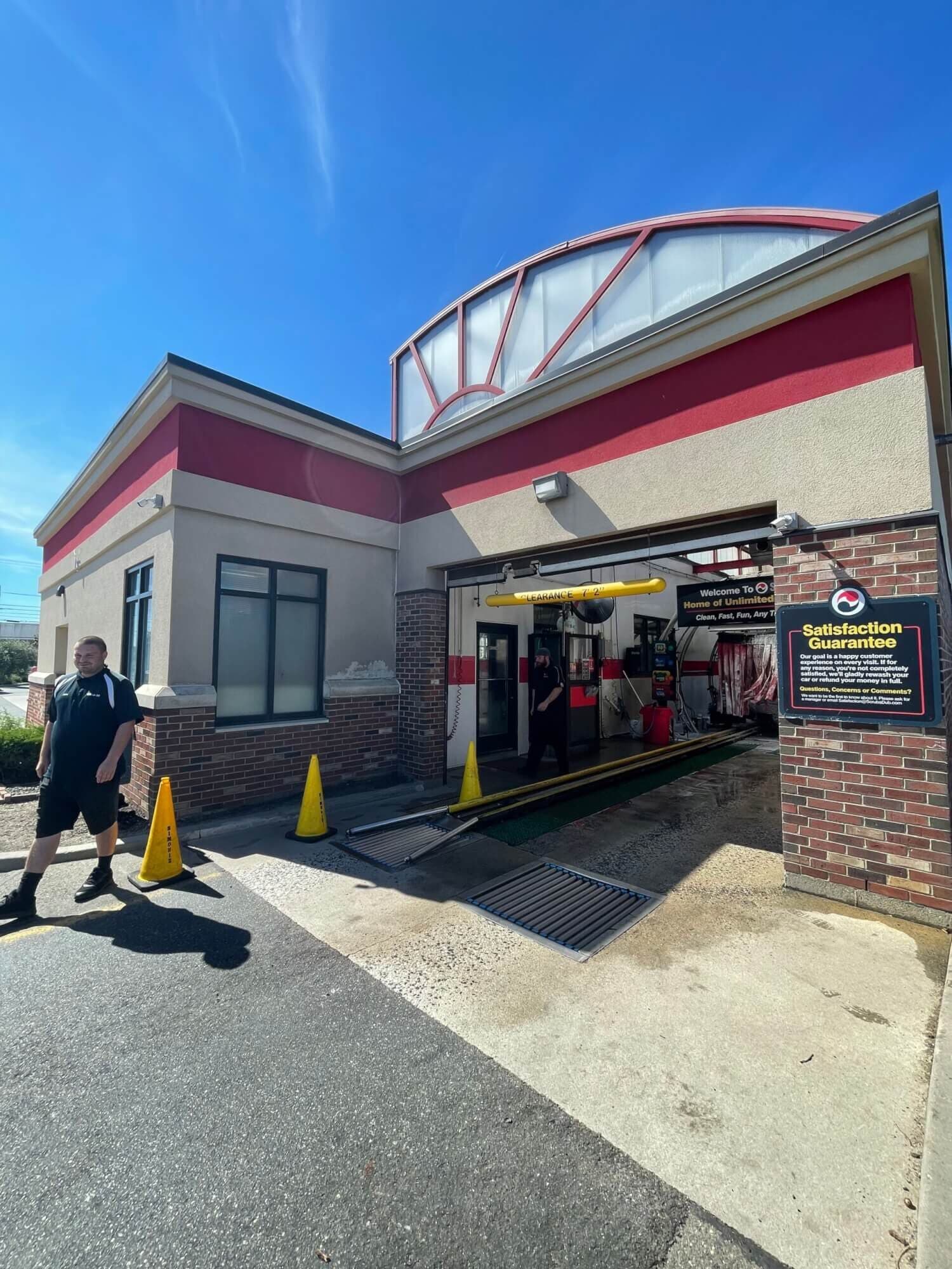 ScrubaDub South Portland tunnel entrance with a "Satisfaction Guarantee" sign and an attendant walking by