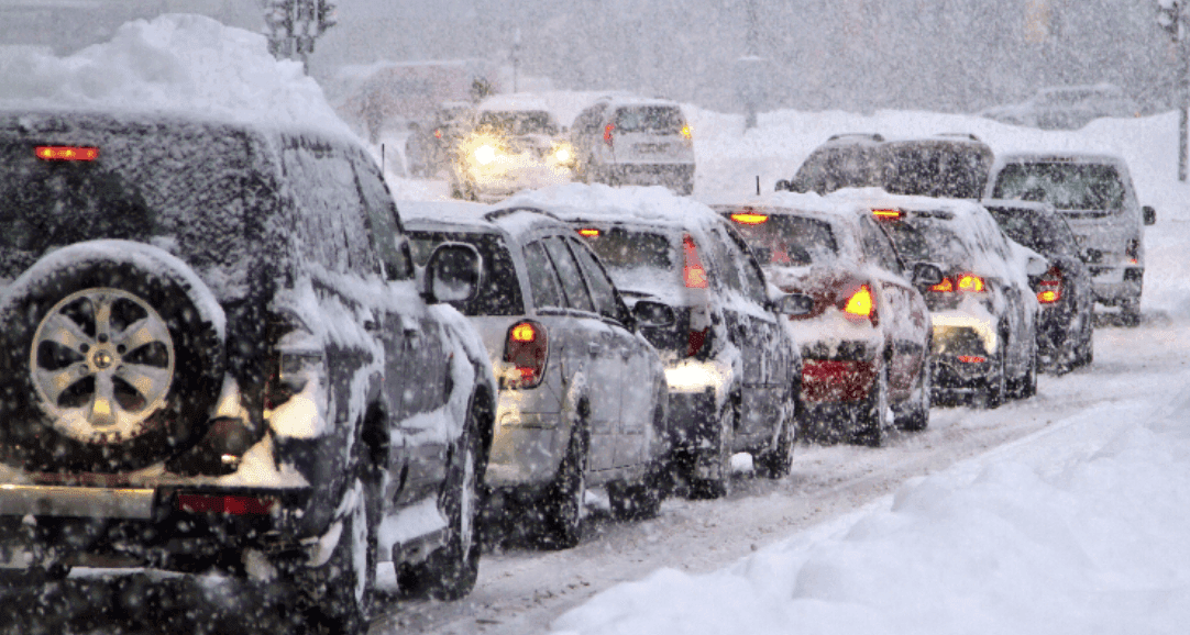 Line of snow-covered cars stuck in traffic during heavy snowfall