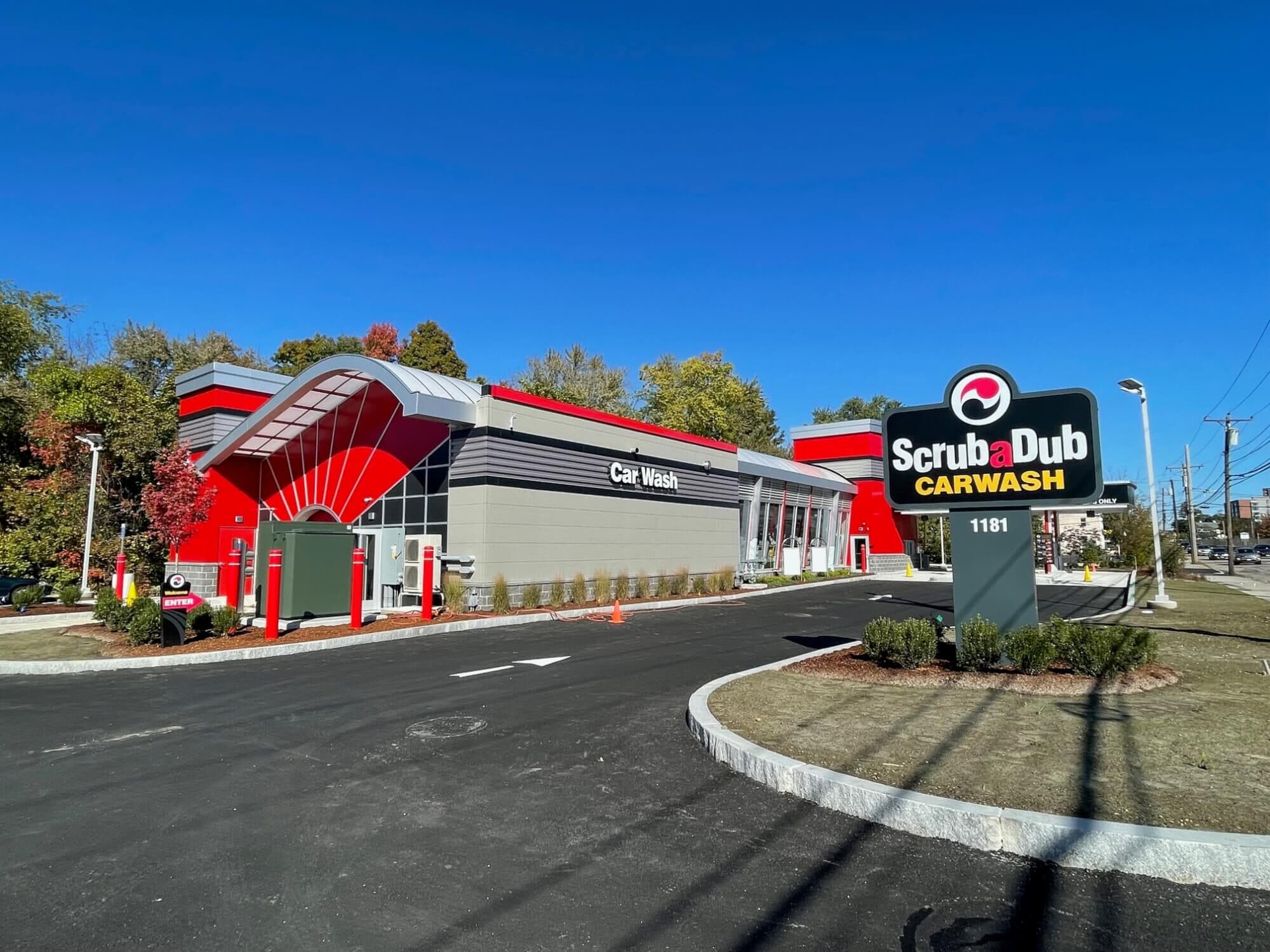 ScrubaDub Framingham car wash with its red fan-arch entrance and "ScrubaDub Carwash" pylon under a clear blue sky