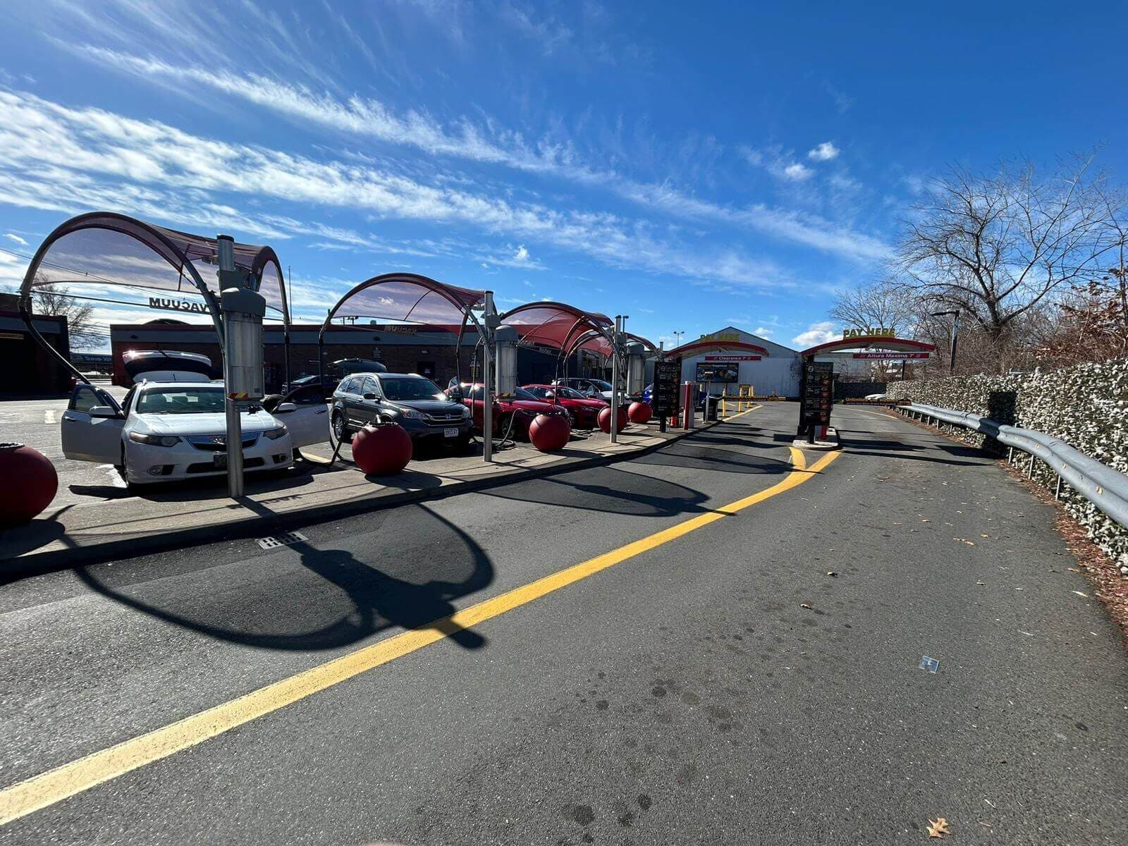 Cars parked at red-canopied vacuum stations with red ball bollards at ScrubaDub Chelsea