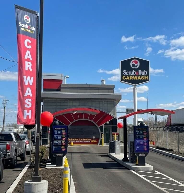 Pay-station lanes leading to the ScrubaDub Medford tunnel entrance, with a CAR WASH banner and tall ScrubaDub Carwash sign