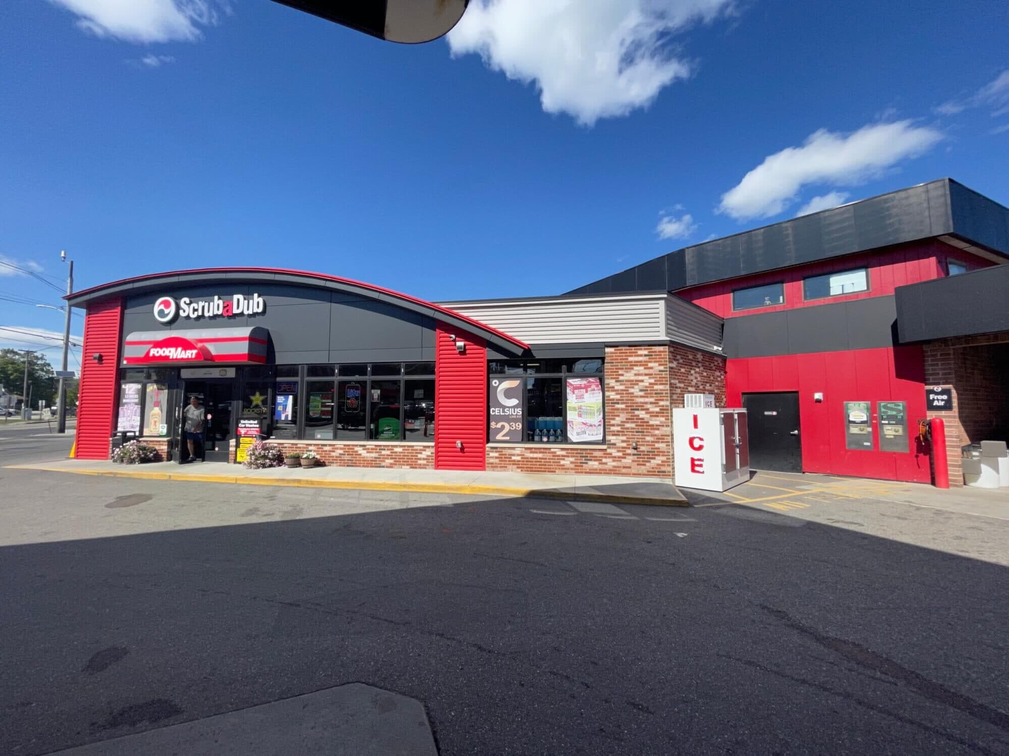 ScrubaDub Food Mart convenience store with red siding, an ice chest, and a free air station