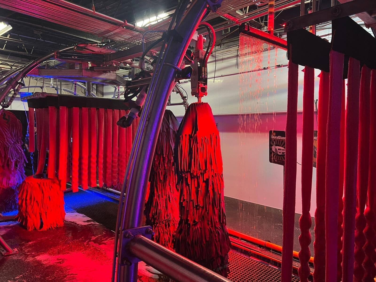 Red-lit cloth wash brushes and mitter curtain inside the tunnel