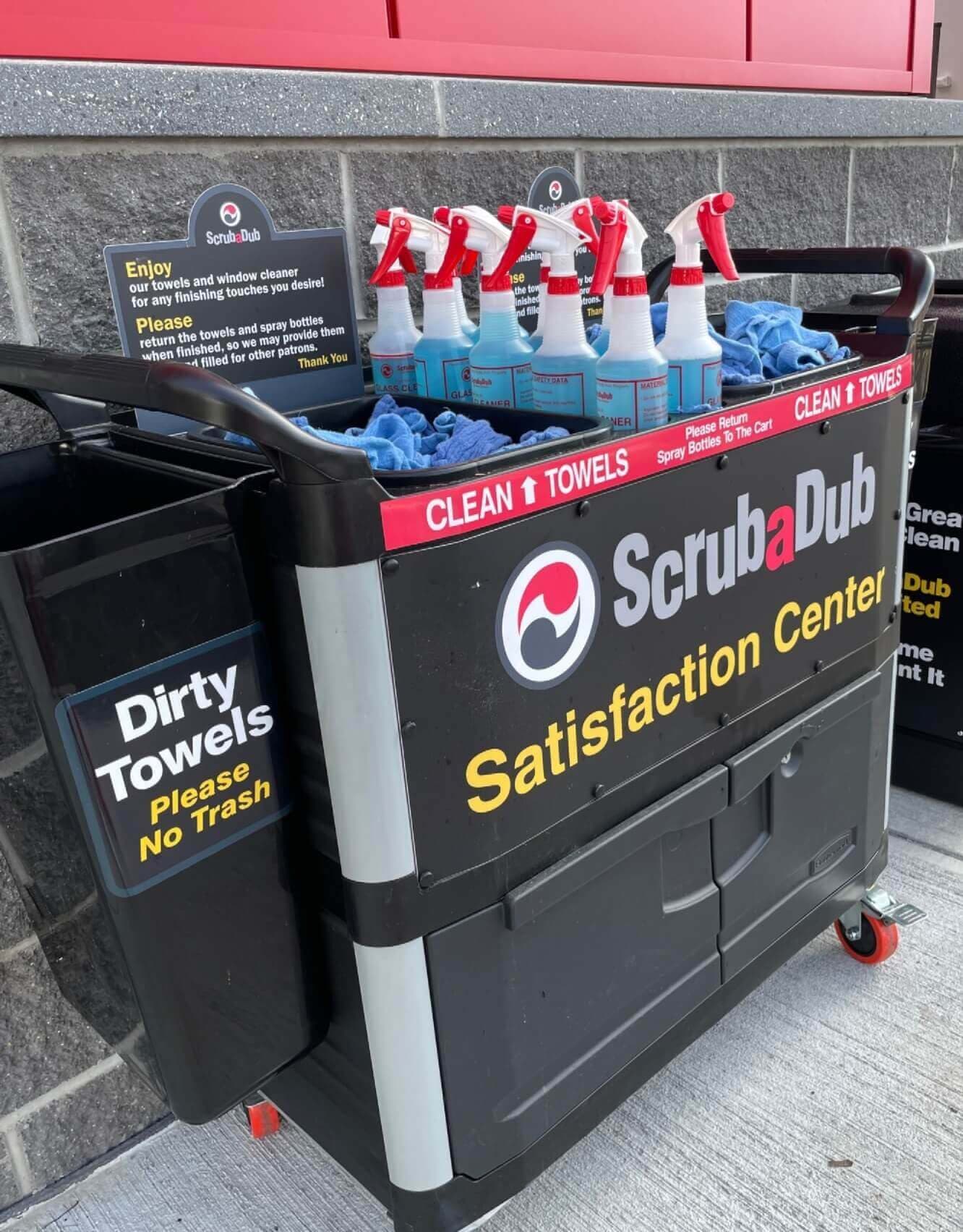 ScrubaDub Satisfaction Center cart stocked with blue towels and window-cleaner spray bottles
