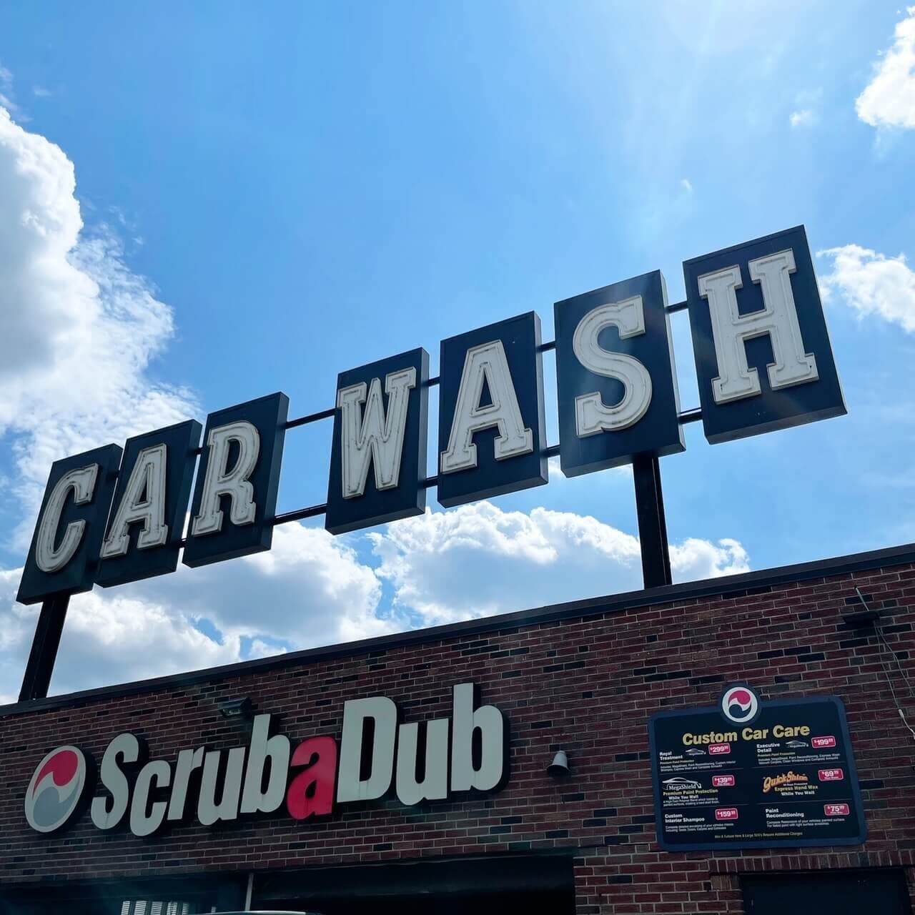 Retro "CAR WASH" block-letter sign above the ScrubaDub Dorchester brick building