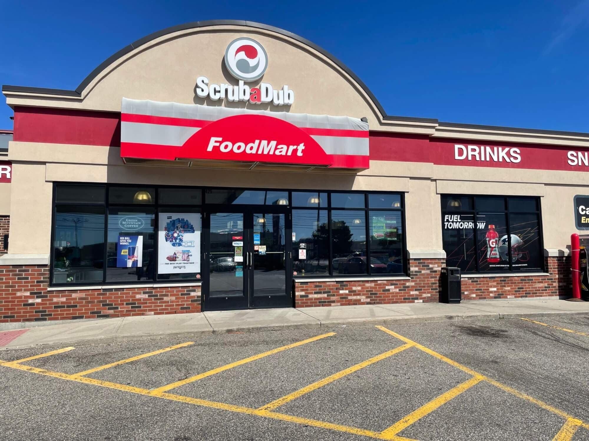 ScrubaDub Food Mart storefront with a red-and-gray awning and an arched facade under a blue sky