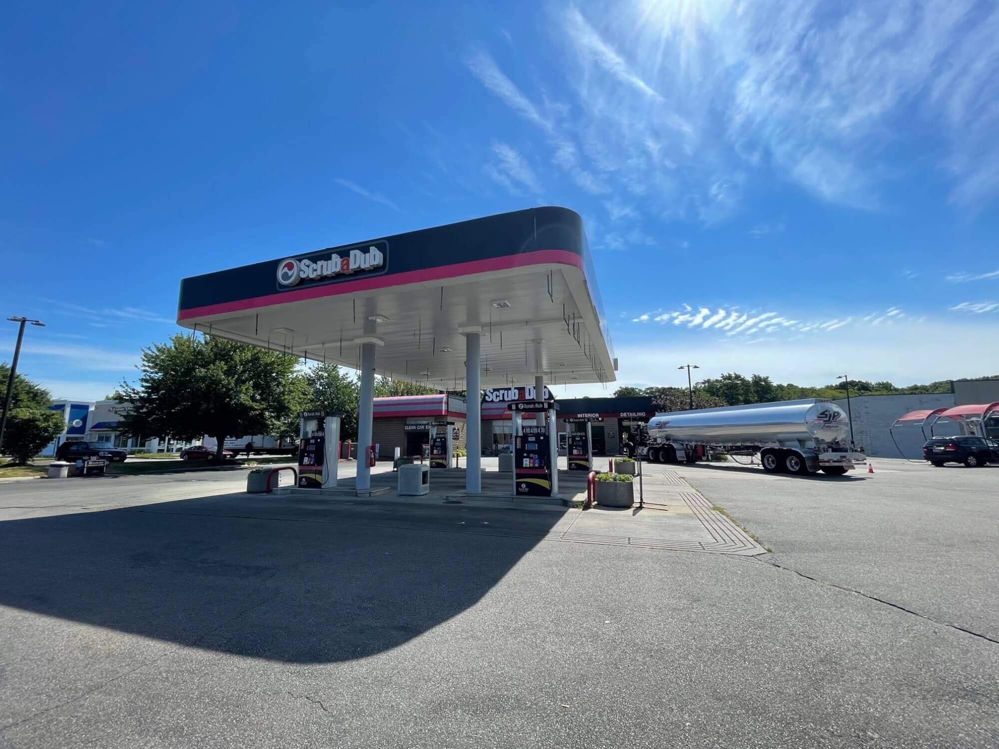 ScrubaDub gas station canopy in Warwick with a fuel tanker truck parked beside the car wash building