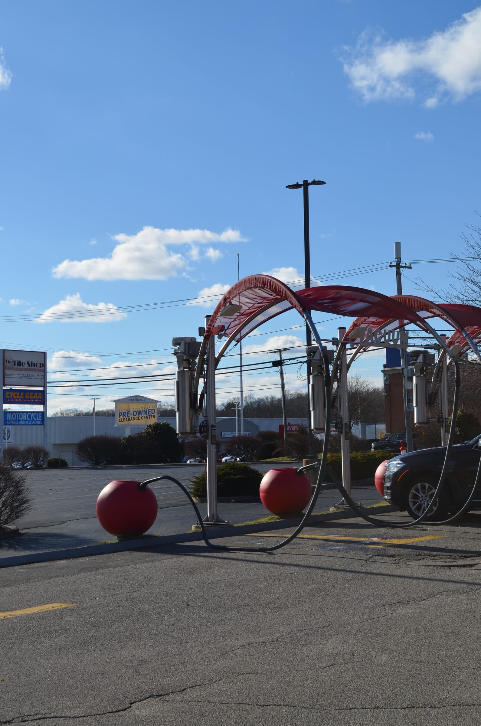 Red vacuum canopy arches with red ball trash cans in a large parking lot under a blue sky