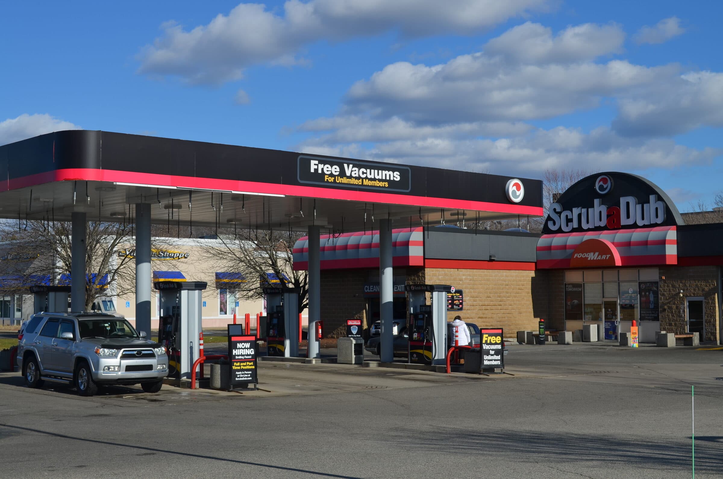ScrubaDub gas station and Food Mart convenience store under a bright blue sky with puffy clouds