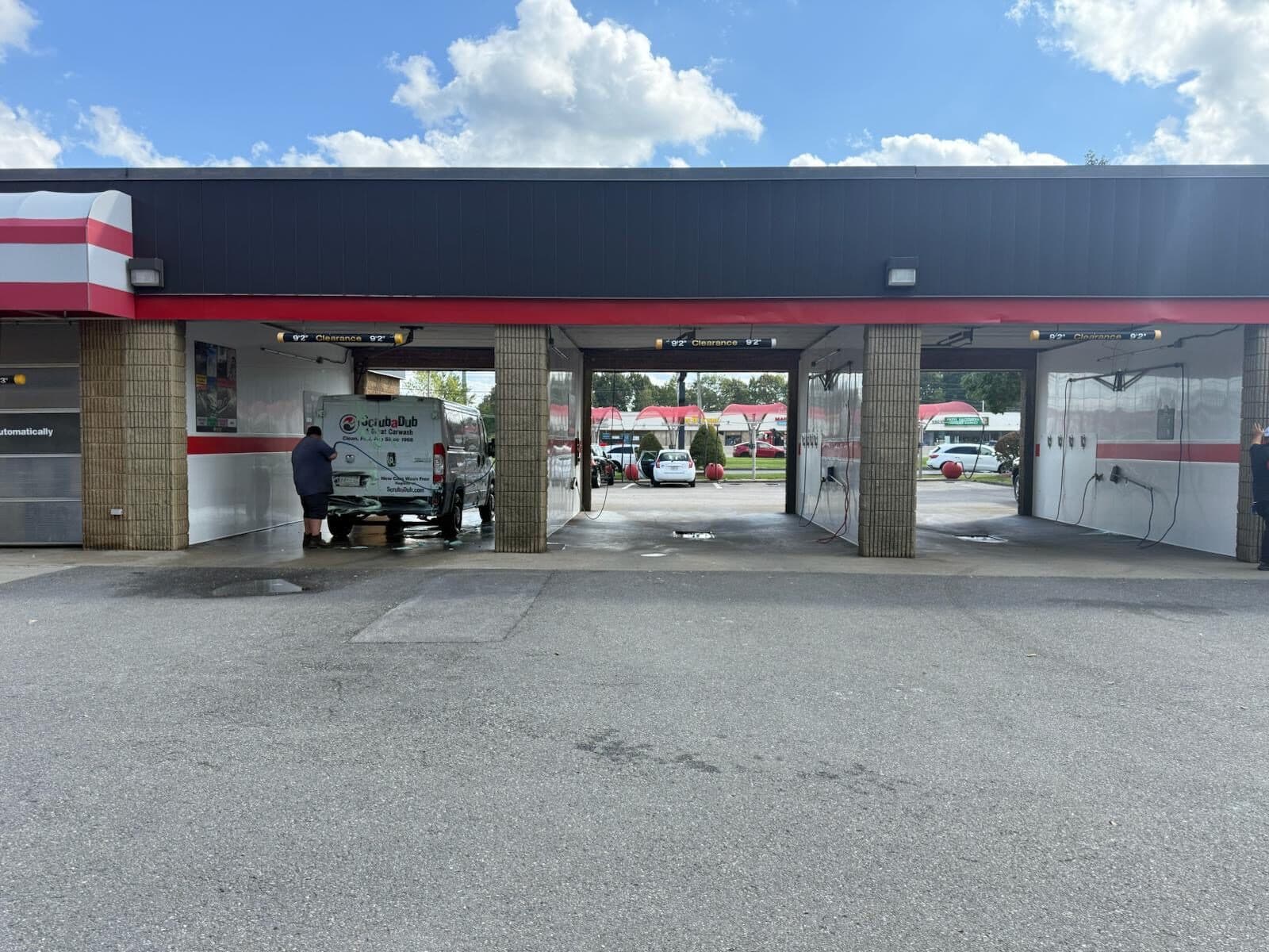 Customer washing a ScrubaDub-branded van in one of three open self-serve wash bays in Shrewsbury