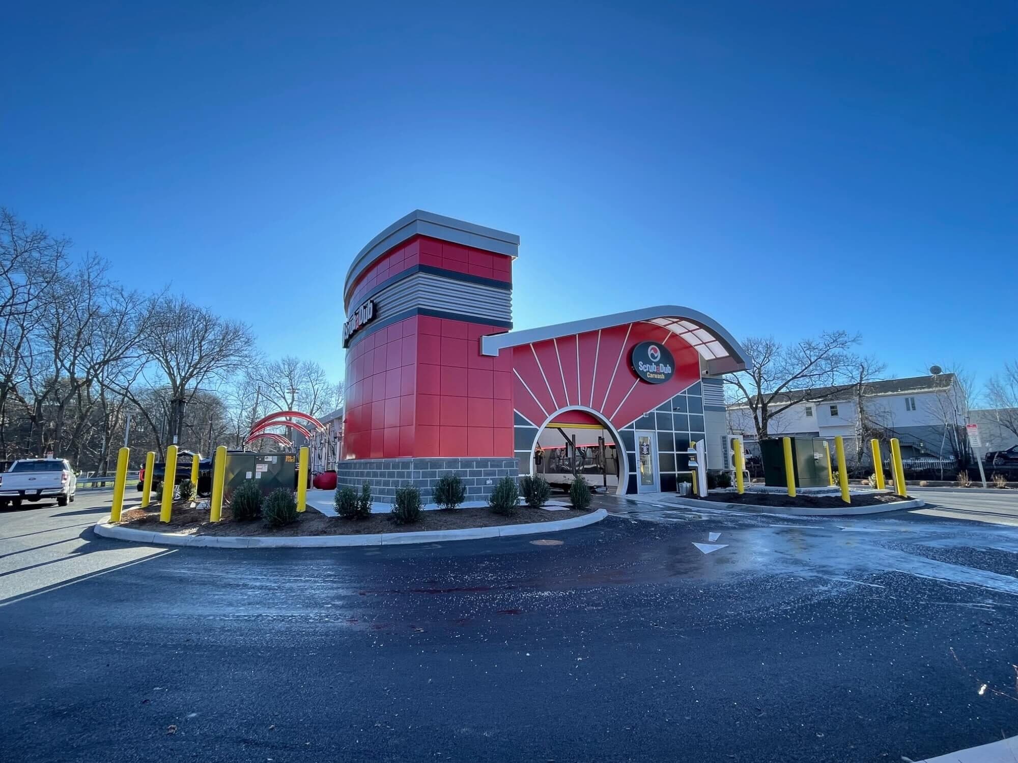 ScrubaDub Worcester Park Ave car wash with a red curved tower and sunburst entrance under a deep blue sky