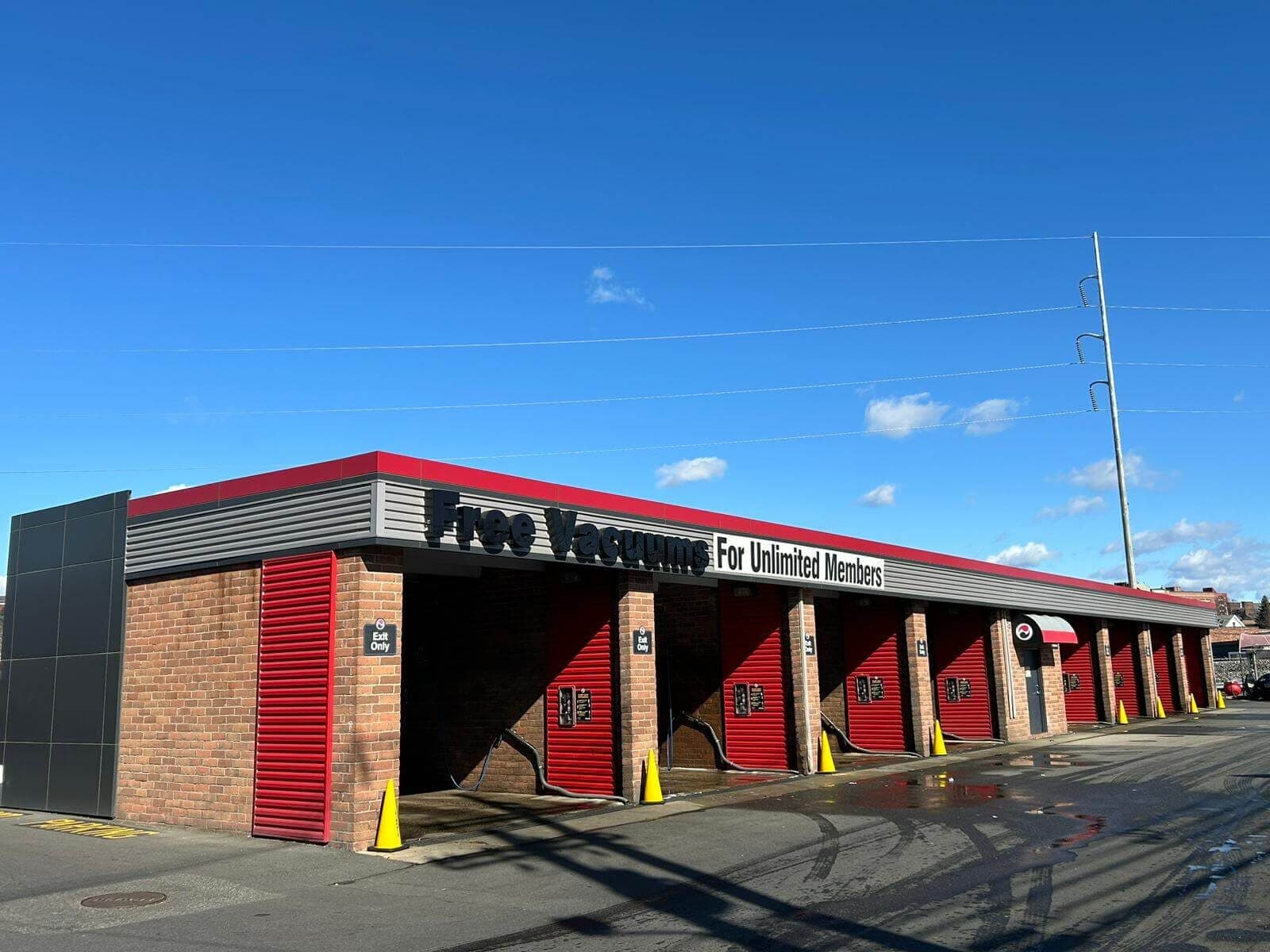 Brick vacuum building with red roll-up doors and a Free Vacuums for Unlimited Members sign under a deep blue sky