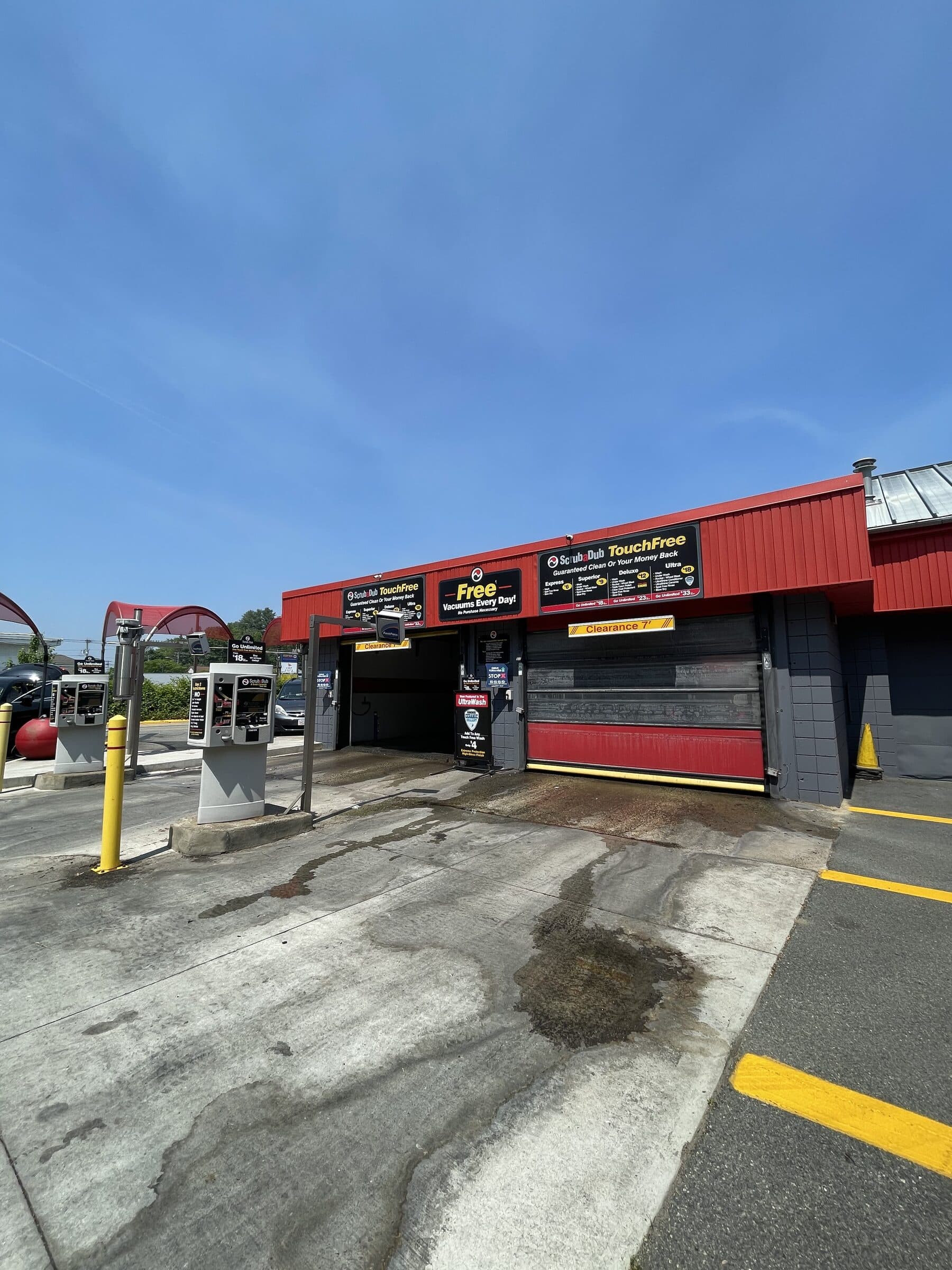 ScrubaDub TouchFree wash bays with menu signs and a "Free Vacuums Every Day" sign