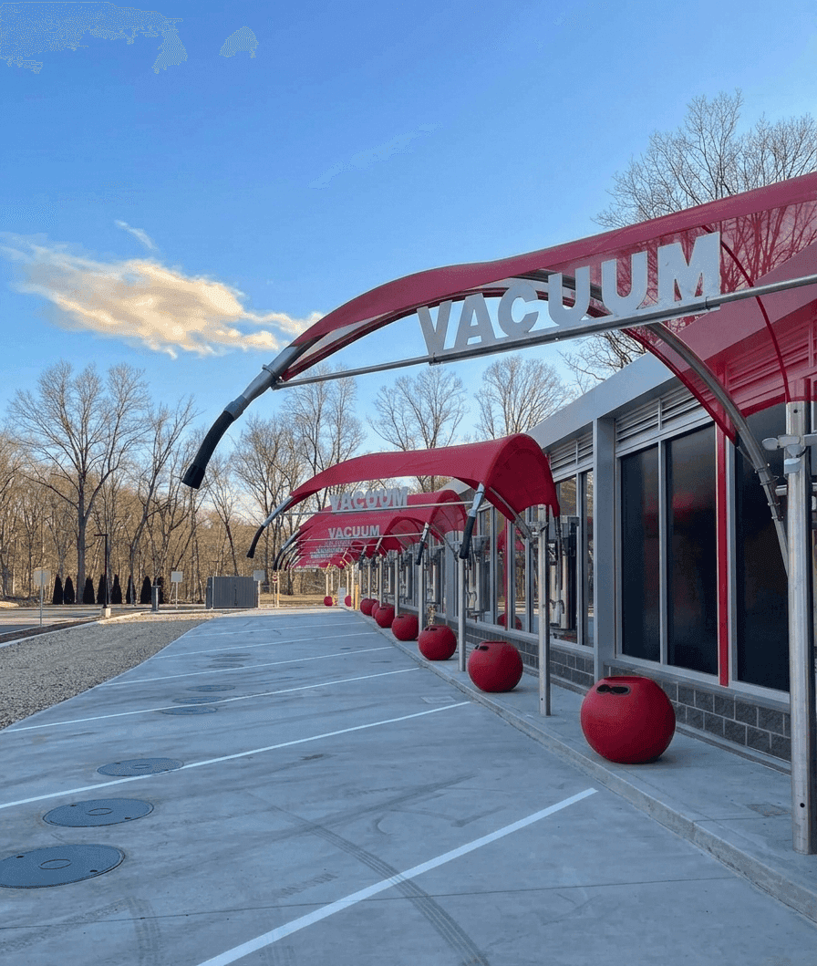 Row of red vacuum canopies with VACUUM signs and red ball canisters along the East Greenwich building