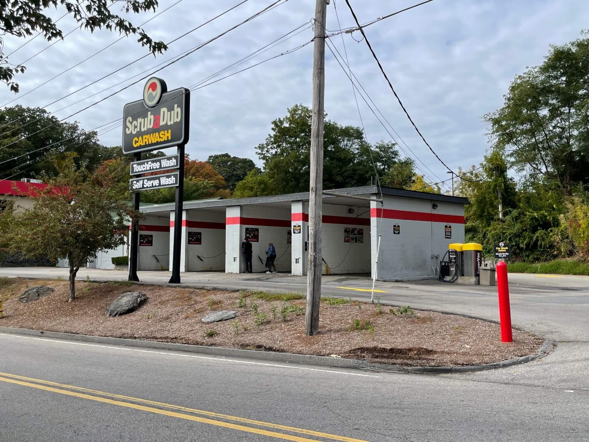 ScrubaDub Carwash pylon advertising TouchFree and Self Serve washes beside a row of self-serve bays