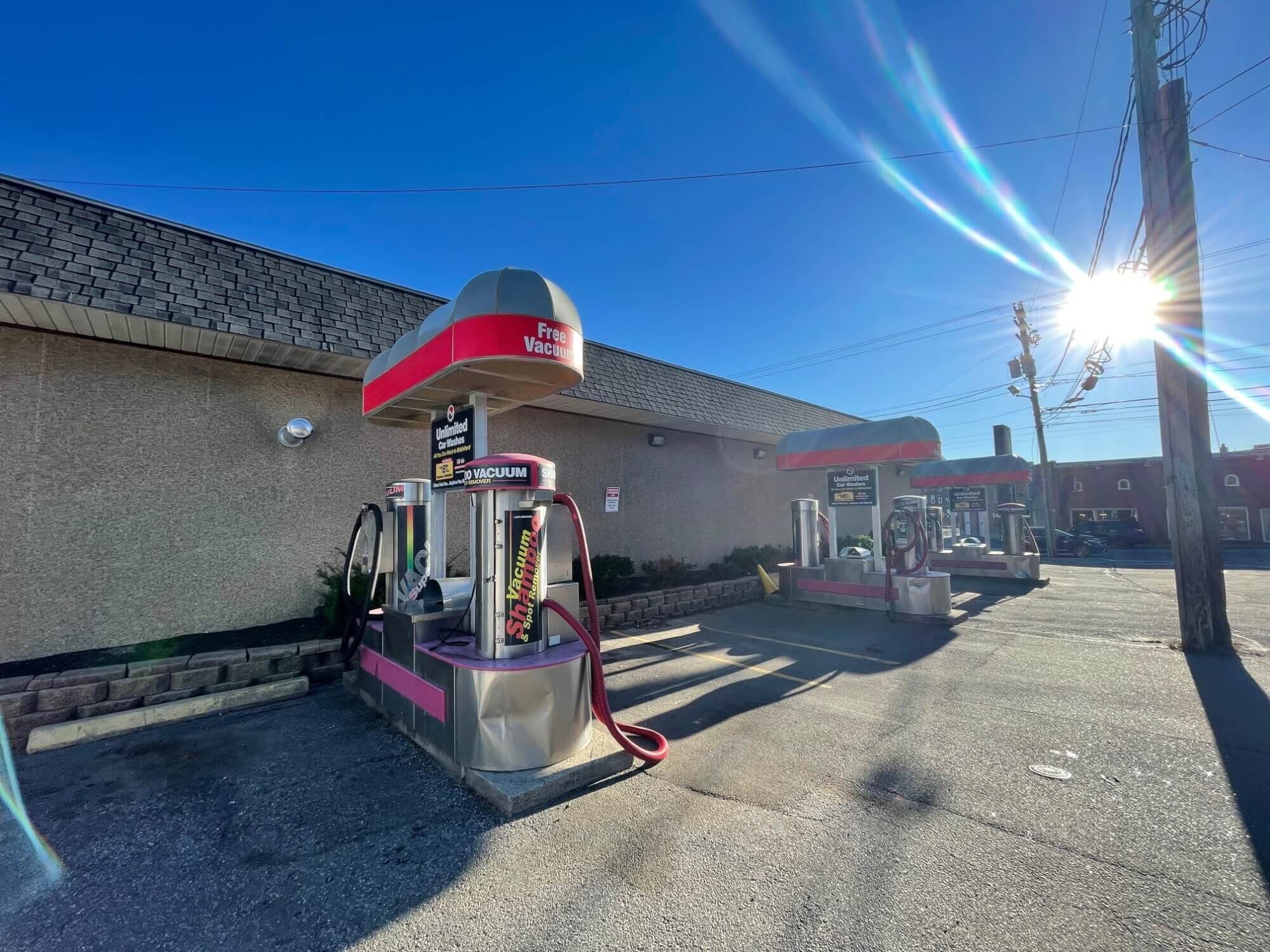 Free vacuum and shampoo stations beside a car wash with bright sun flare