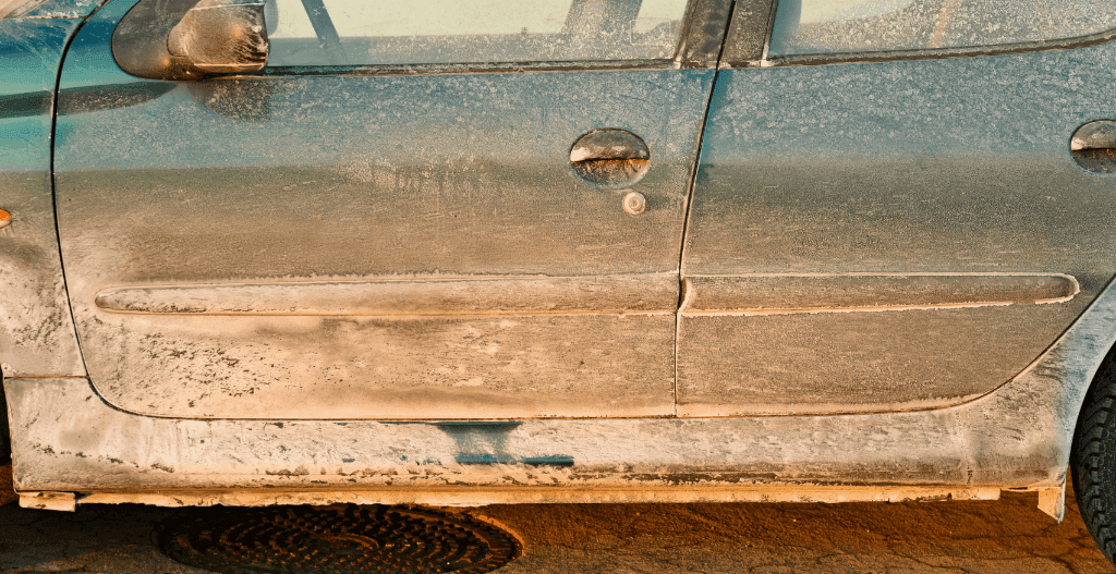 Side doors of a car caked in white road-salt residue and grime