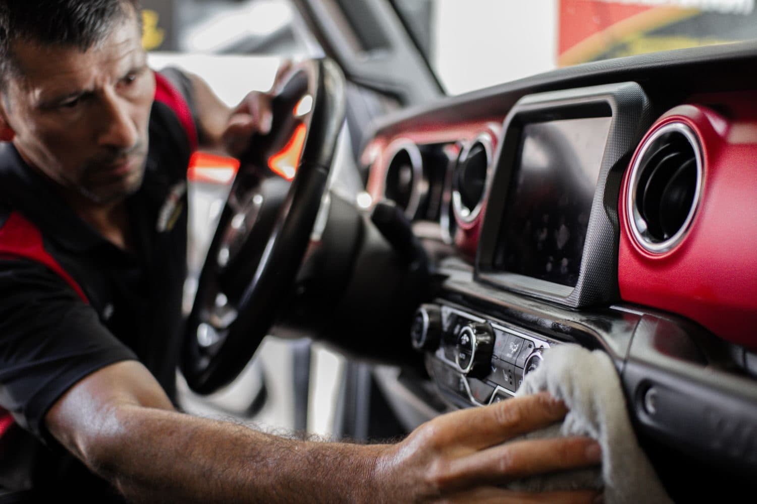 ScrubaDub detailer wiping down the dashboard of a Jeep with a red interior